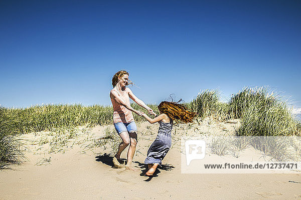 Netherlands  Zandvoort  happy mother and daughter dancing in beach dunes