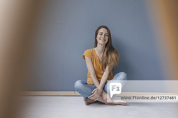 Happy woman sitting on ground  barefoot with legs crossed  laughing