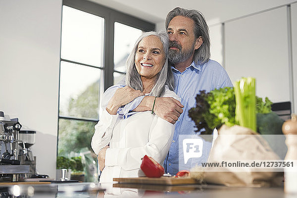 Happy senior couple preparing food in kitchen