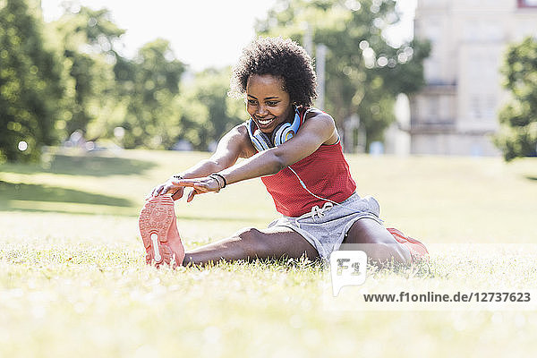 Young woman stretching on meadow in park