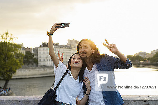 France  Paris  happy young couple taking a selfie at river Seine at sunset
