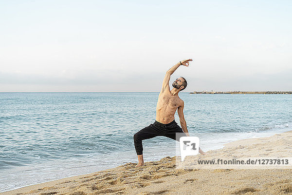 Spain. Man doing yoga on the beach in the evening