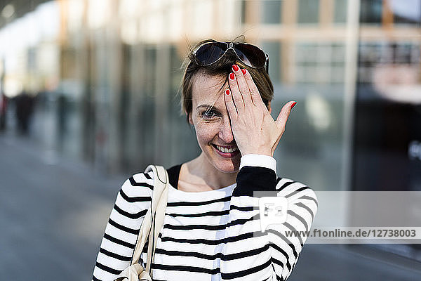 Portrait of smiling woman covering eye with her hand