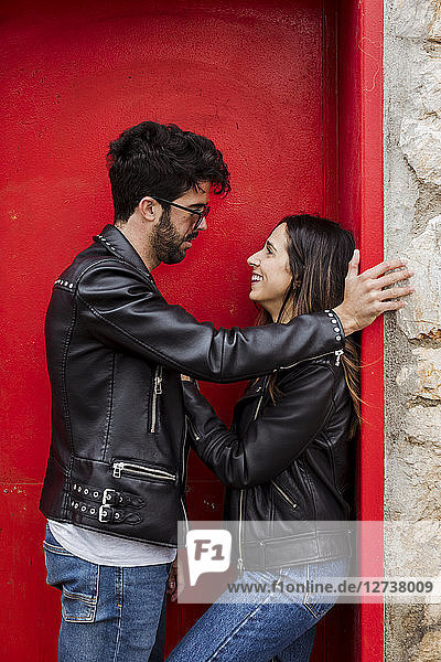 Happy young couple standing at red door