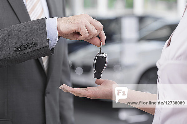 At the car dealer  Salesman handing over car key to client