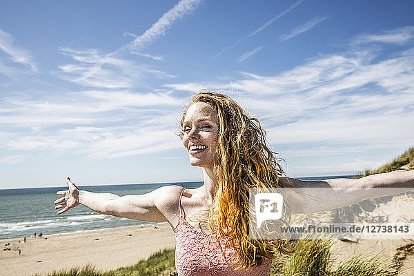 Netherlands  Zandvoort  happy woman standing in dunes with outstretched arms