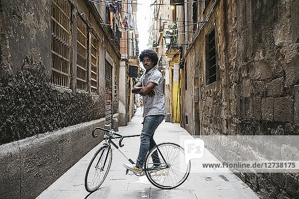 Spain  Barcelona  man standing with racing cycle in an alley