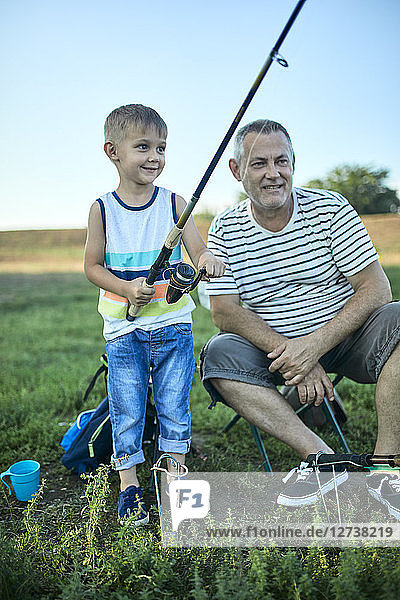 Grandfather and grandson fishing together at lakeshore