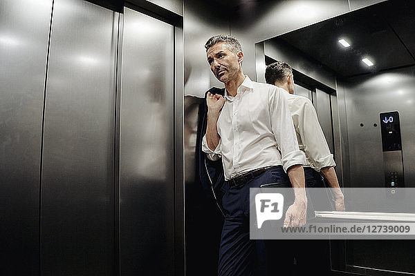 Businessman in elevator holding laptop