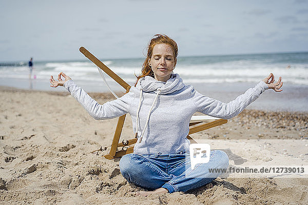 Woman sitting cross-legged on sand  meditating on the beach