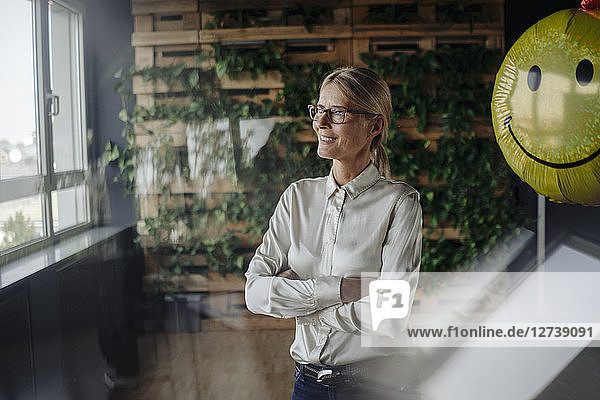Smiling businesswoman in green office with balloon