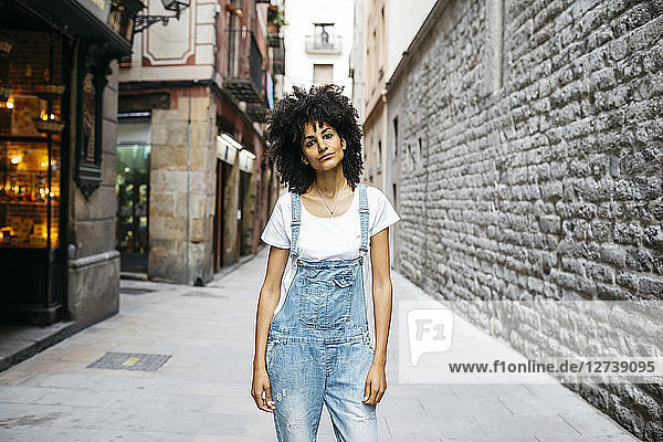 Spain  Barcelona  portrait of woman with curly hair wearing dungarees