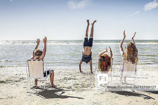 Netherlands  Zandvoort  family clapping hands for father doing a handstand on the beach