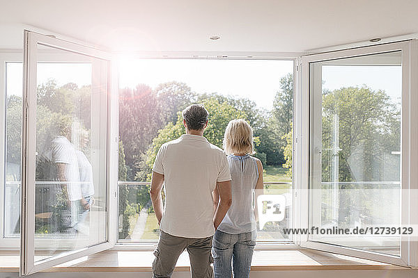 Mature couple looking out of window into the sun