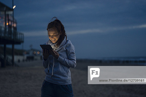 Woman using digital tablet on the beach at sunset