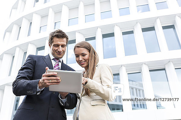 Poland  Warzawa  businessman and businesswoman with tablet computer standing in front of hotel