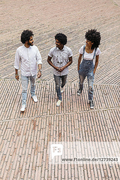 Three friends walking on a square having fun together