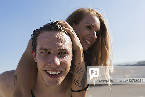 Portrait of happy young man giving his girlfriend a piggyback ride