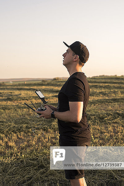Man holding remote control for a drone in a field