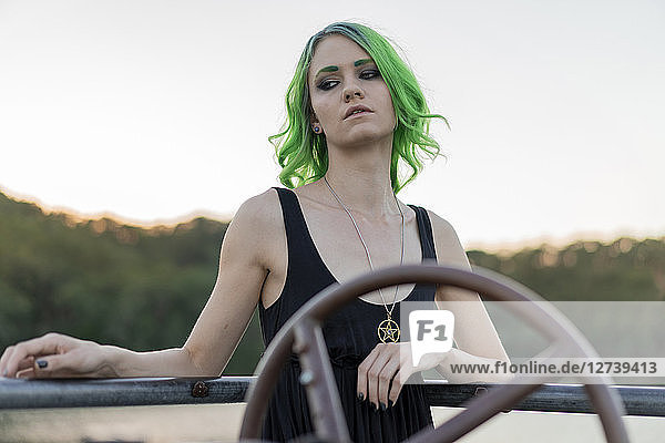 Portrait of young woman with dyed green hair and eyebrows at lake