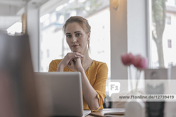 Young woman sitting in coworking space using laptop