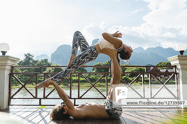 Laos  Vang Vieng  Young couple doing acro-yoga on a terrace