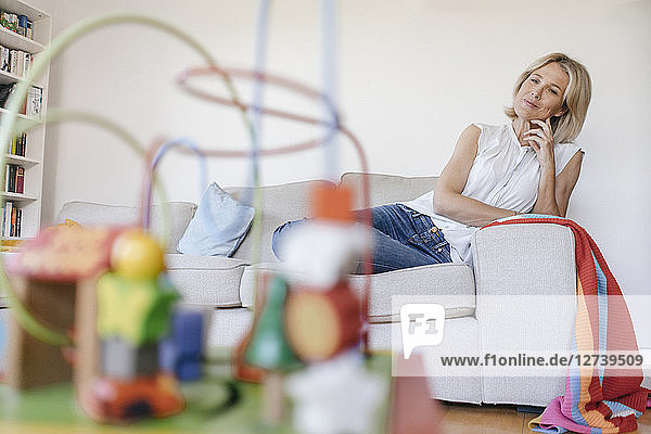 Mature woman on couch at home looking at children's toy