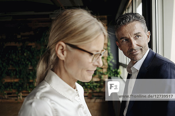 Portrait of confident businessman and businesswoman at the window