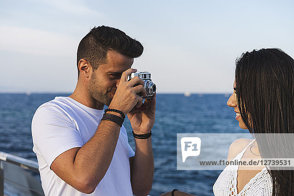 Young urban couple taking pictures by the sea