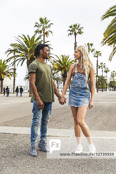 Spain  Barcelona  multicultural young couple standing hand in hand on promenade
