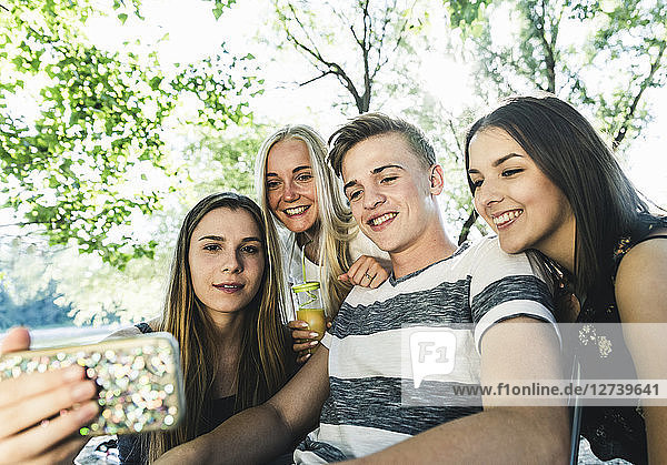 Group of smiling friends looking at cell phone outdoors