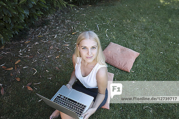 Young woman sitting in garden  using laptop
