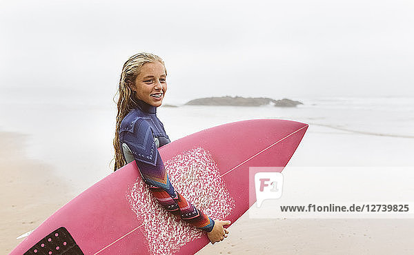 Spain  Aviles  young surfer holding surfboard on the beach
