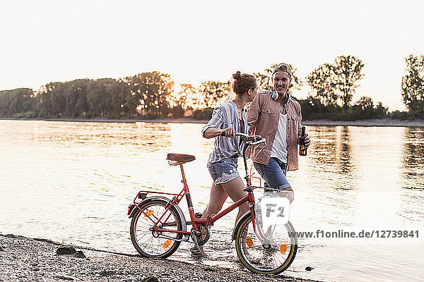 Young couple with bicycle wading in river