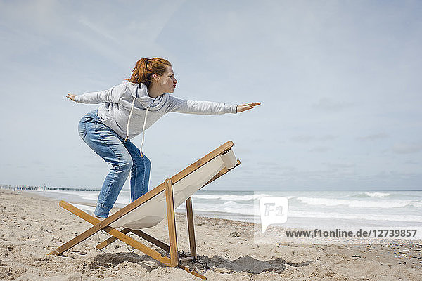 Woman standing on deck chair  pretending to surf