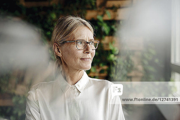 Businesswoman in green office looking out of window