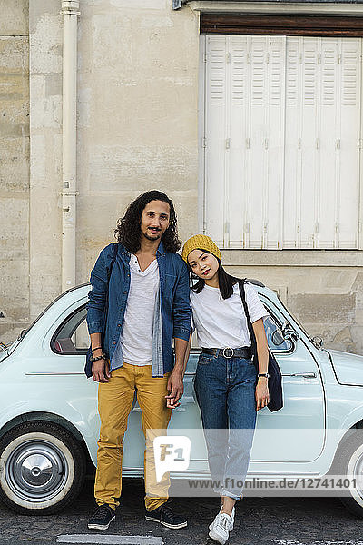 Portrait of young couple standing at small car