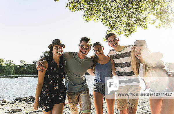 Portrait of group of happy friends arm in arm at the riverside