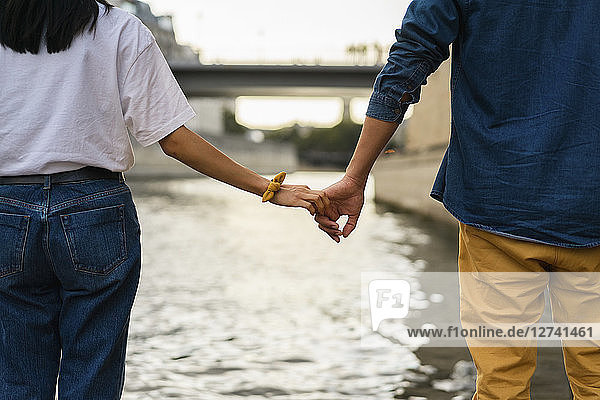 France,  Paris,  couple holding hands at river Seine