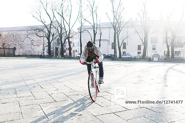 Young man riding bicycle on urban square