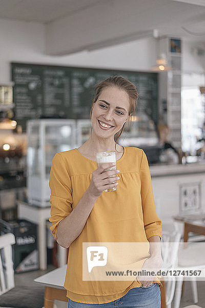Young business owner standing in her coffee shop  drinking coffee