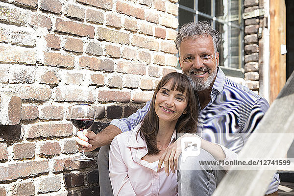 Mature couple sitting on stairs  drinking wine