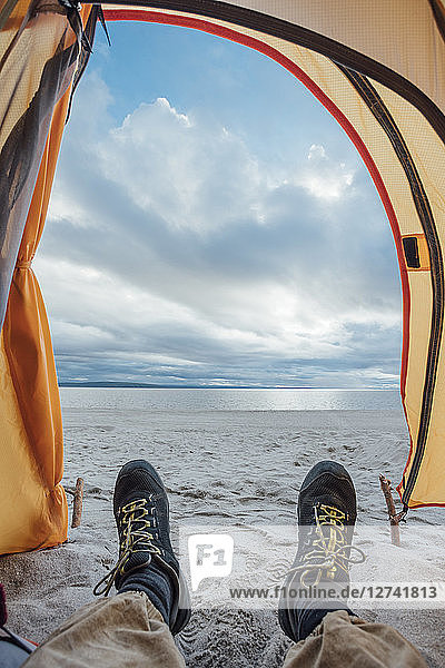 Feet of man  lying in tent on beach