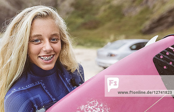 Spain  Aviles  portrait of smiling young surfer on the beach