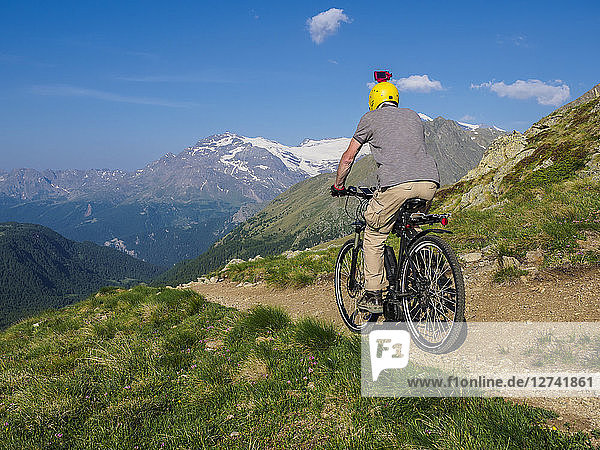 Italy Lombardy  Passo di Val Viola  Man riding e-bike in the mountains with action cam on his helmet