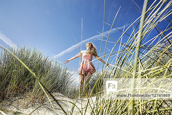 Netherlands  Zandvoort  happy woman standing in dunes with outstretched arms