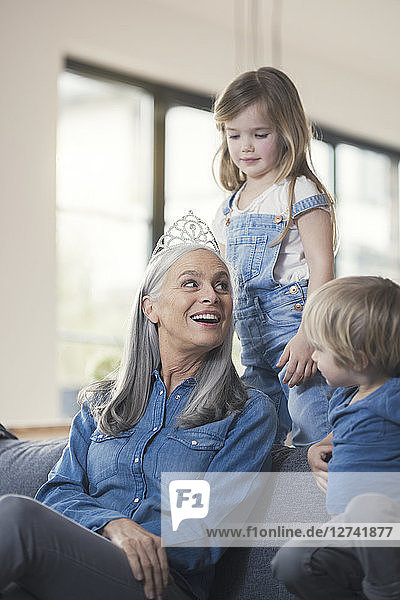 Grandmother wearing crown  sitting on couch with grandchildren
