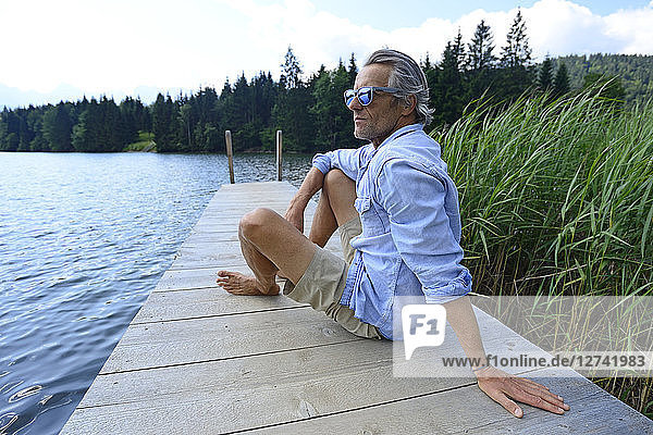 Germany  Mittenwald  mature man relaxing on jetty at lake