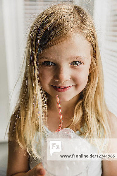 Portrait of blond little girl blowing milk bubbles