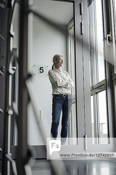 Businesswoman standing on the corridor looking out of window